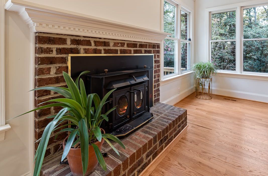 Wood burning brick fireplace in a finished barndominium living space with exposed timber framing and metal roof construction